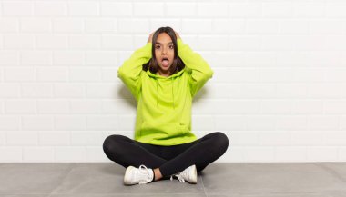 İspanyol kadın heyecanlı ve şaşırmış görünüyor, ağzı açık, elleri başının üstünde, kendini şanslı hissediyor.