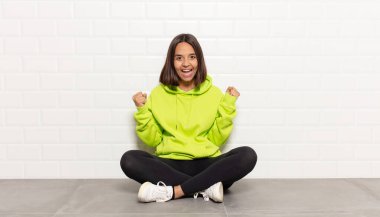 İspanyol kadın mutlu, şaşırmış ve gururlu hissediyor, bağırıyor ve başarıyı büyük bir gülümsemeyle kutluyor.