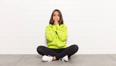 İspanyol kadın mutlu ve heyecanlı, şaşırmış ve şaşırmış elleri ağızda, tatlı bir ifadeyle kıkırdıyor.