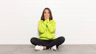 İspanyol kadın endişeli, üzgün ve korkmuş hissediyor, elleriyle ağzını kapatıyor, endişeli ve berbat görünüyor.