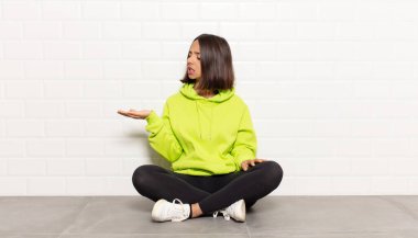 İspanyol kadın kendini mutlu hisseder ve gelişigüzel gülümser. Elinde tuttuğu bir nesneye ya da konsepte bakar.