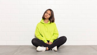 Hispanik kadın kendini şaşkın ve şüpheli hissediyor, merak ediyor ya da karar vermeye çalışıyor.