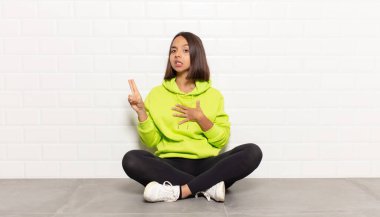 İspanyol kadın mutlu, kendinden emin ve güvenilir görünüyor, gülümsüyor ve zafer işareti gösteriyor, olumlu bir tavırla.