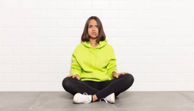 Hispanik kadın, hangi seçeneği seçeceğine karar veremediğini ve sorunu çözmeye çalıştığını düşünüyor.