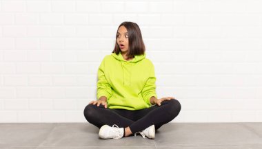 İspanyol kadın şaşkın, mutlu, şaşkın ve şaşırmış hissediyor, ağzı açık bir şekilde yana bakıyor.