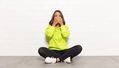 İspanyol kadın elleri ile ağzını kapatıyor, şok olmuş, şaşırmış bir ifadeyle, sır saklıyor ya da 