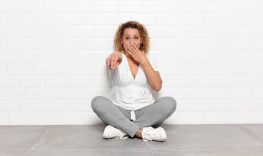 Orta yaşlı bir kadın sana gülüyor, kamerayı gösteriyor ve seninle dalga geçiyor ya da alay ediyor.