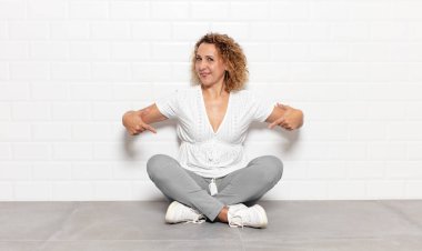 Orta yaşlı bir kadın gururlu, kibirli, mutlu, şaşırmış ve tatmin olmuş görünüyor.