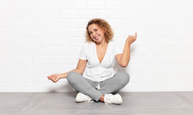 Orta yaşlı kadın gülümsüyor, kaygısız hissediyor, rahat ve mutlu, dans ediyor ve müzik dinliyor, bir partide eğleniyor.