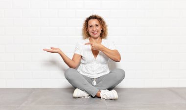 Orta yaşlı kadın gülümsüyor, mutlu, kaygısız ve tatmin olmuş hissediyor, fotokopi alanındaki konsepte veya fikre işaret ediyor.