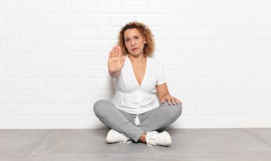 Orta yaşlı bir kadın ciddi, sert, hoşnutsuz ve kızgın görünüyor.