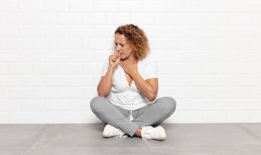 Orta yaşlı kadın boğazı ağrıyan ve grip belirtileri gösteren ağzı kapalı öksüren bir hasta.