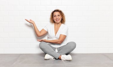 Orta yaşlı kadın gururla ve kendinden emin bir şekilde gülümsüyor, mutlu ve tatmin olmuş hissediyor ve fotokopi alanında bir konsept gösteriyor.