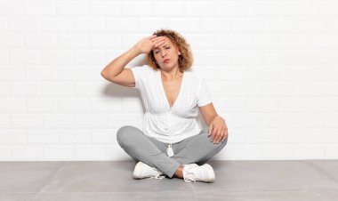 Orta yaşlı kadın stresli, yorgun ve hayal kırıklığına uğramış görünüyor, alnından ter damlıyor, umutsuz ve bitkin hissediyor.