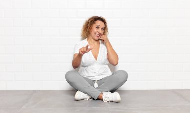 Orta yaşlı bir kadın neşeli bir şekilde gülümsüyor ve kamerayı işaret ediyor. Sonra seni arıyor, telefonla konuşuyor.