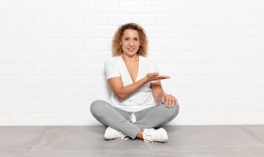 Orta yaşlı bir kadın neşeli bir şekilde gülümsüyor, mutlu hissediyor ve fotokopi alanında bir konsept gösteriyor.