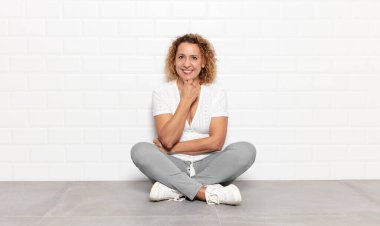 Orta yaşlı kadın gülümsüyor, hayattan zevk alıyor, mutlu, arkadaş canlısı, tatmin olmuş ve tasasız.