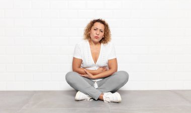 Orta yaşlı bir kadın endişeli, hasta, hasta ve mutsuz hissediyor. Ağrılı bir mide ağrısı veya grip geçiriyor.