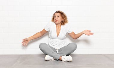 middle age woman feeling clueless and confused, having no idea, absolutely puzzled with a dumb or foolish look