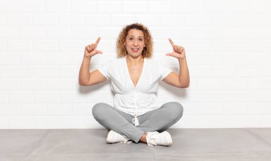 Orta yaşlı bir kadın iki eliyle kendi gülüşünü çiziyor, olumlu ve mutlu görünüyor, sağIık kavramı