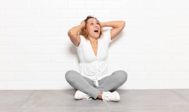 Orta yaşlı, ağzı açık bir kadın korkunç ve şok olmuş görünüyor. Korkunç bir hata yüzünden, el ele tutuşuyor.