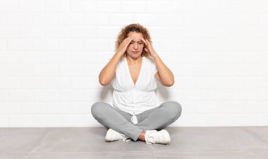 Stresli ve hayal kırıklığına uğramış görünen orta yaşlı bir kadın, baskı altında çalışıyor, başı ağrıyor ve sorunları var.