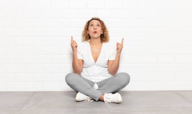 Orta yaşlı bir kadın şaşırmış ve ağzı açık bir şekilde şaşkın ve şaşkın bir bakışla yukarı bakıyor.