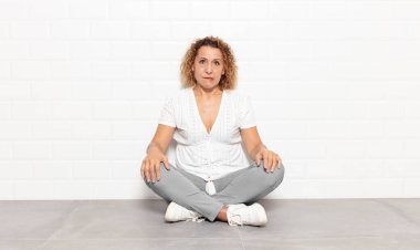 Orta yaşlı kadın şaşkın ve şaşkın görünüyor. Sinirli bir hareketle dudağını ısırıyor. Sorunun cevabını bilmiyor.