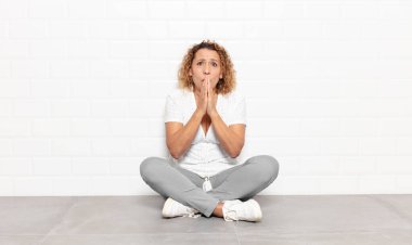 Orta yaşlı bir kadın endişeli, üzgün ve korkmuş hissediyor, elleriyle ağzını kapatıyor, endişeli ve berbat görünüyor.