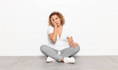 Orta yaşlı bir kadın yorgun, sıkıcı ve sıkıcı bir işten sonra sıkılmış, hayal kırıklığına uğramış ve uykulu hisseder.