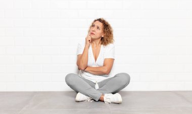 Orta yaşlı kadın, yoğun bakışlı, şüpheli bir ifadeyle merak ediyor, yukarı ve yana bakıyor