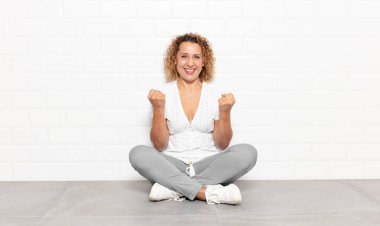 Orta yaşlı kadın zaferle bağırıyor, gülüyor, mutlu ve heyecanlı hissediyor başarıyı kutlarken.