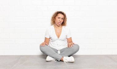 Orta yaşlı bir kadın tiksinmiş ve rahatsız olmuş hissediyor. Dilini dışarı çıkarıyor. İğrenç ve iğrenç bir şeyden hoşlanmıyor.