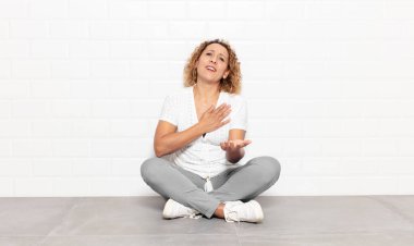 Orta yaşlı bir kadın mutlu ve aşık, bir eli kalbinin yanında gülümsüyor ve diğer eli önde uzanıyor.