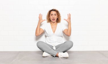 Orta yaşlı bir kadın elleri havada bağırıyor. Öfkeli, sinirli, stresli ve üzgün.