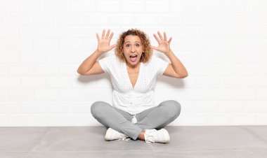 Panik içinde bağıran orta yaşlı bir kadın, şok olmuş, korkmuş ya da öfkeli, elleri başının yanında.