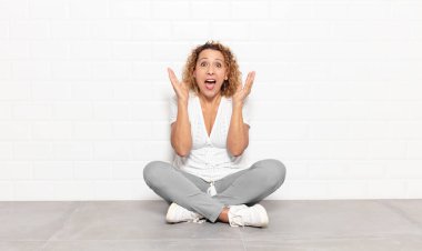 Orta yaşlı bir kadın beklenmedik bir sürpriz yüzünden şaşkın, heyecanlı, gülen, şaşkın ve mutlu hissediyor.