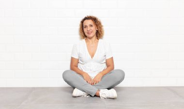 Orta yaşlı bir kadın mutlu, mutlu, kendinden emin ve rahat bir ifadeyle neşeli bir şekilde gülümsüyor.