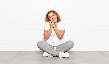 Orta yaşlı bir kadın aşık ve sevimli görünüyor. Sevimli ve mutlu. Romantik bir şekilde gülümsüyor.