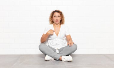 Orta yaşlı bir kadın şaşkın, şaşkın ve güvensiz hissediyor. Kendini gösterip kim olduğunu soruyor, ben mi??