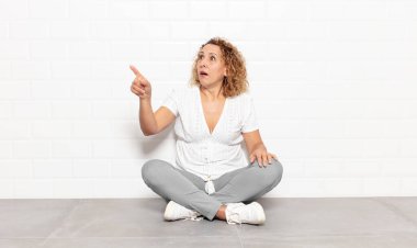 Orta yaşlı bir kadın şaşkın ve şaşırmış hissediyor. Şaşırmış ve ağzı açık bir şekilde hayranlıkla yukarı bakıyor.