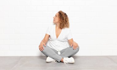 Orta yaşlı bir kadın kafası karışık ya da dolgun ya da şüphe ve soru dolu, merak ediyor, elleri kalçasında, dikiz aynasından.