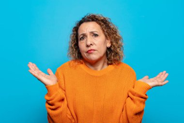 Orta yaşlı kadın şaşkın ve şaşkın hissediyor, şüpheci, farklı seçenekleri tartıyor veya komik bir ifadeyle seçiyor.