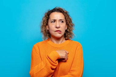 Orta yaşlı bir kadın şüpheye düşüyor ya da düşünüyor, dudağını ısırıyor ve kendini güvensiz ve gergin hissediyor, kenarda yer arıyor.