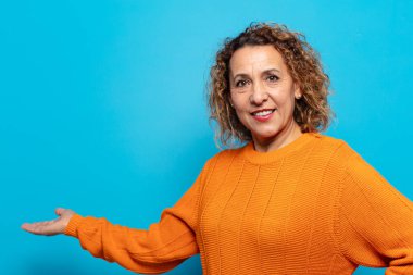 Orta yaşlı bir kadın kendini mutlu ve neşeli hissediyor, gülümsüyor ve seni hoş karşılıyor, dostça bir jestle içeri davet ediyor.