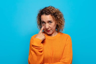 Orta yaşlı bir kadın sana göz kulak oluyor, güvenmiyor, izliyor, tetikte ve tetikte.