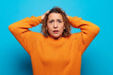 Orta yaşlı bir kadın stresli, endişeli, endişeli ya da korkmuş, elleri başının üstünde, hata yaptığında panikliyor.