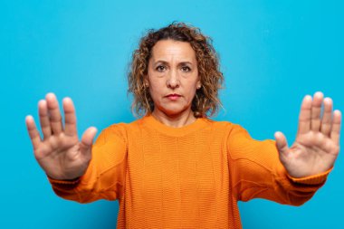 Orta yaşlı kadın ciddi görünüyor, mutsuz, kızgın ve hoşnutsuz giriş yasaklandı ya da her iki avuçta da dur diyor.