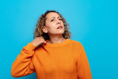 Orta yaşlı bir kadın stresli, endişeli, yorgun ve hayal kırıklığına uğramış, gömleğini çekmiş, sorunlu görünüyor.