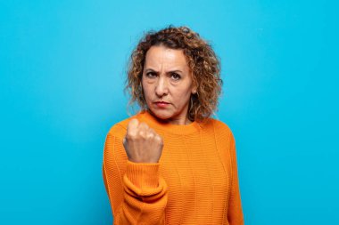 Orta yaşlı bir kadın kızgın, sinirli, asi ve agresif orta parmağını sallayarak karşılık veriyor.